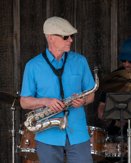 Curt Bergmann holding his alto saxophone on an outdoor stage